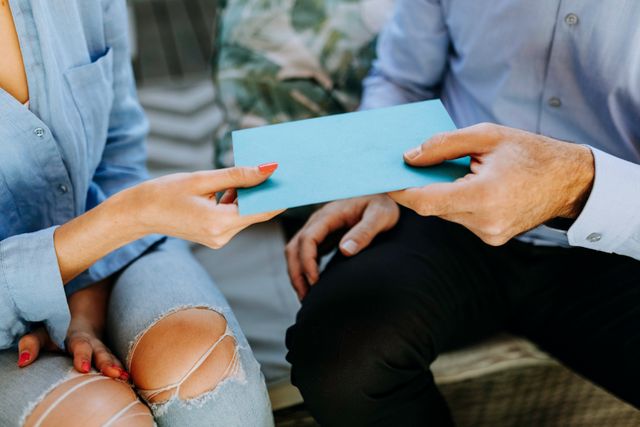 two people exchanging a blue envelope