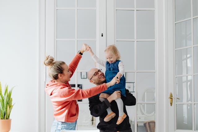 smiling-parents-playing-with-daughter-indoors-in-playful-dance